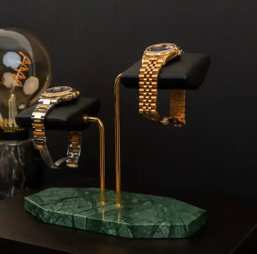 Two-watch display stand with gold posts and green marble base.