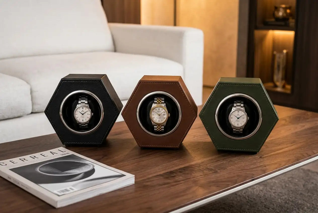 Three hexagonal watch winder units in black, brown, and olive green leather housing each display a different wristwatch.