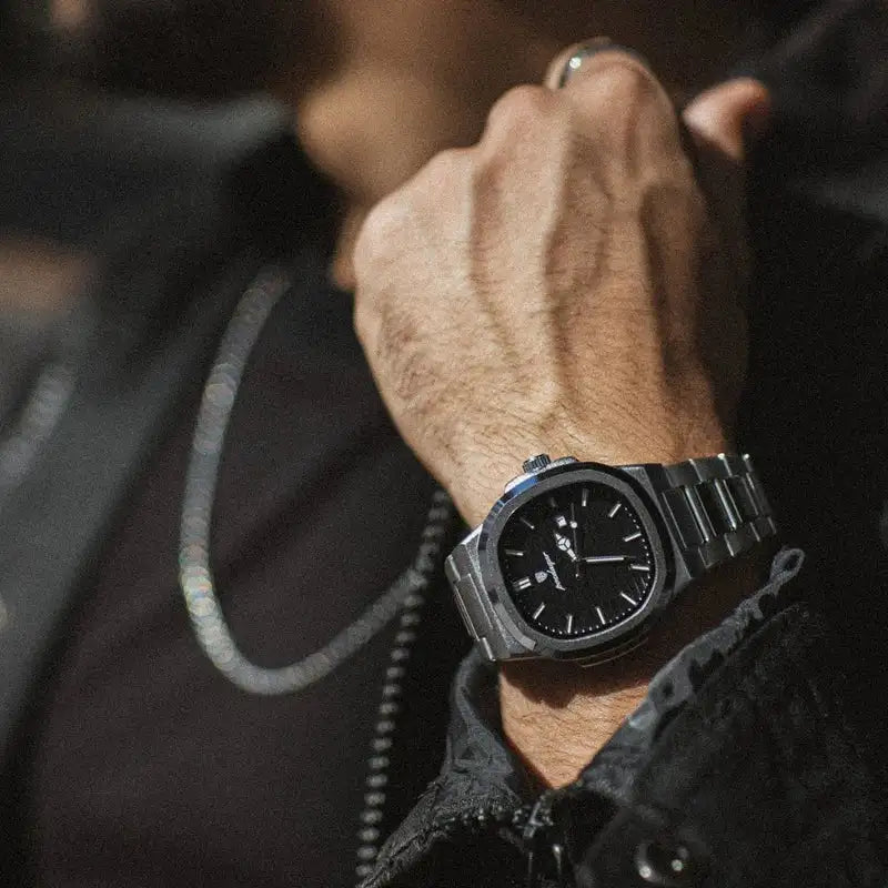 A sleek black dial watch with a polished stainless steel case and bracelet, featuring minimalist hour markers and the brand name engraved on the bezel.