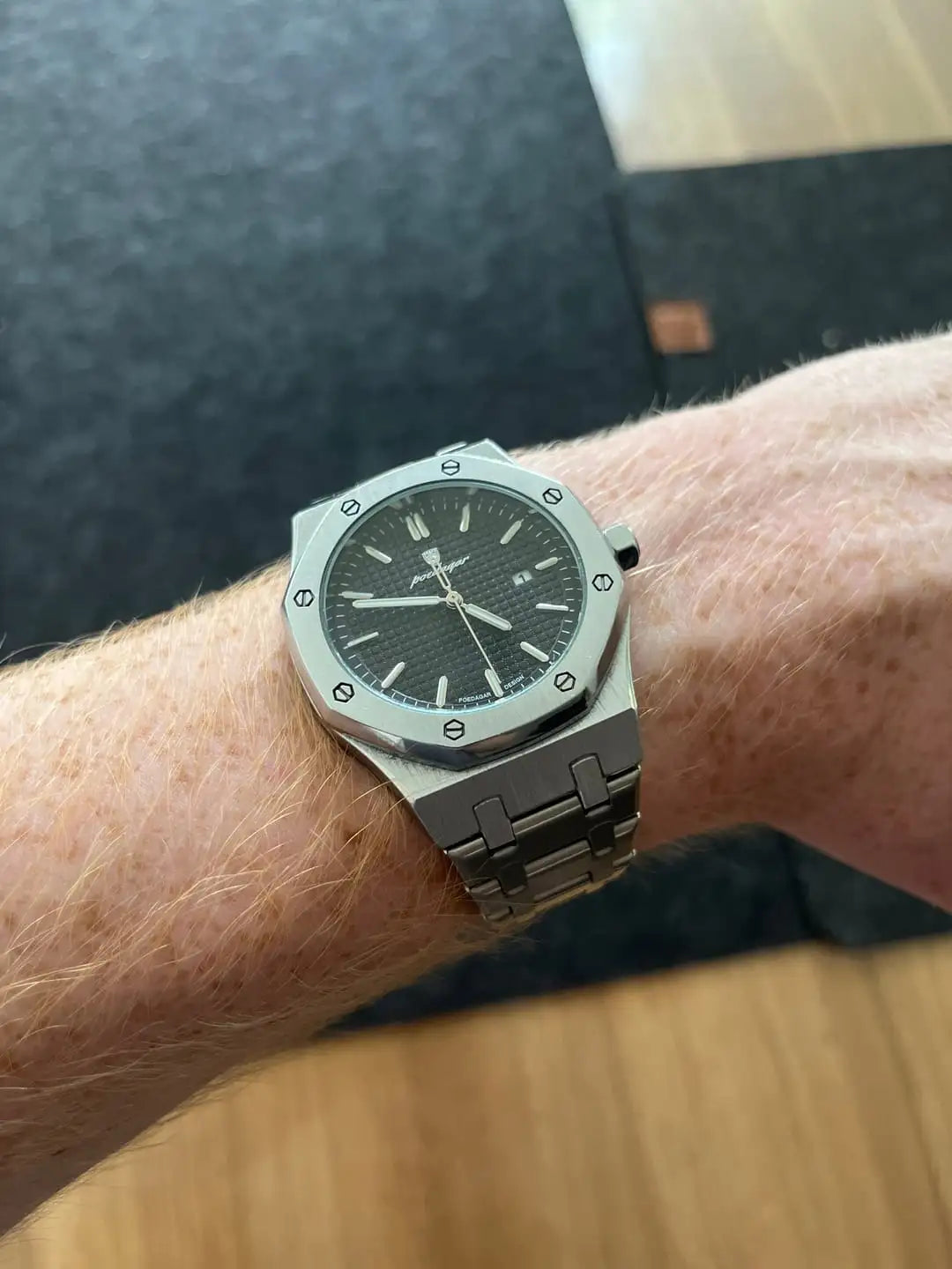A sleek silver audemars piguet royal oak watch with a black textured dial and polished stainless steel bracelet.