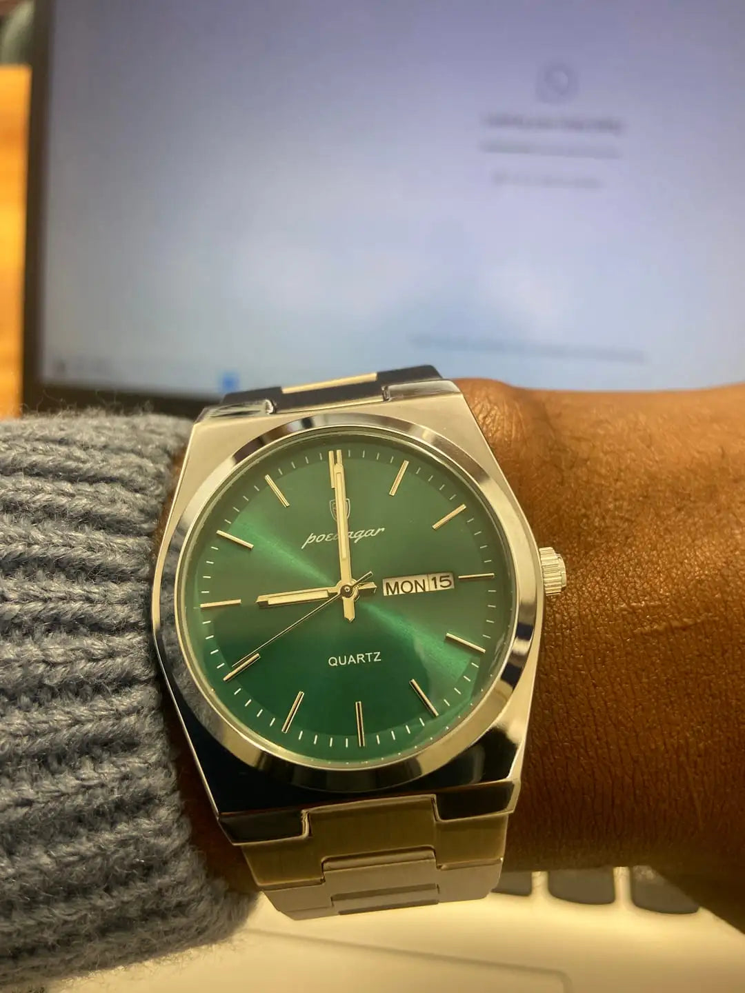 A sleek silver-toned pochagar quartz watch with a vibrant green gradient dial and gold-tone hands, worn on a wrist.