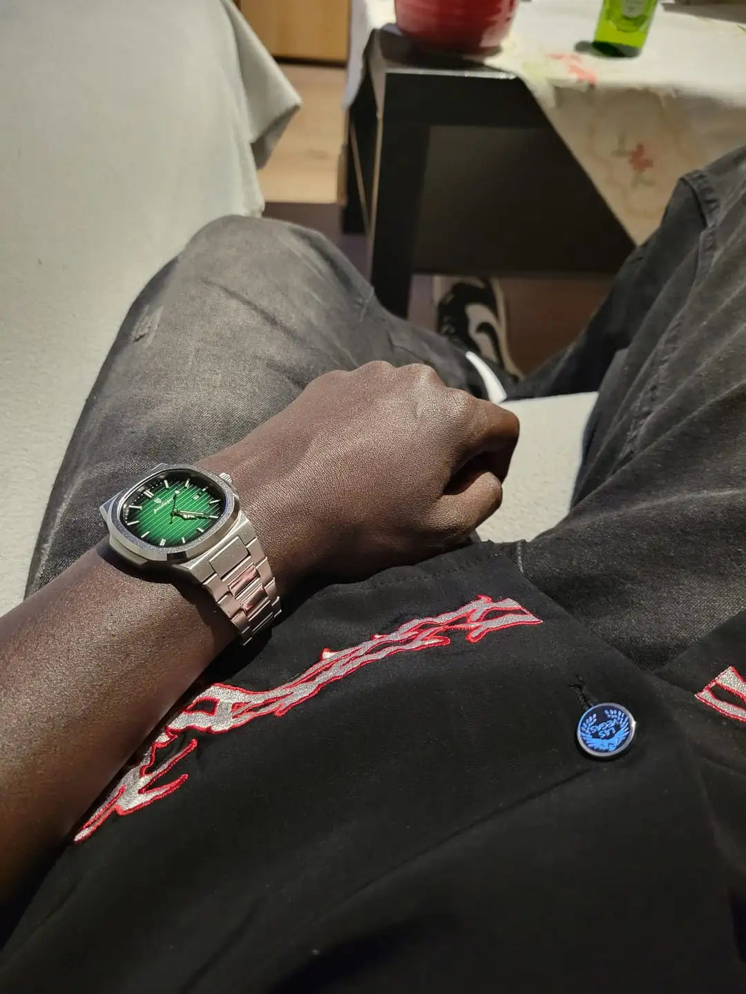 A sleek silver-toned watch with a vibrant green dial and black hour markers, featuring a polished metal bracelet.